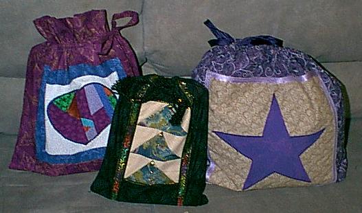 The small bag is the one sent to me by a friend, her blocks are Flying Geese. she was learning a new , one seam method of making them, and put the practice pieces to good use. That bag contains a large paperback book. The purple heart was my first bag I made, enough said. 