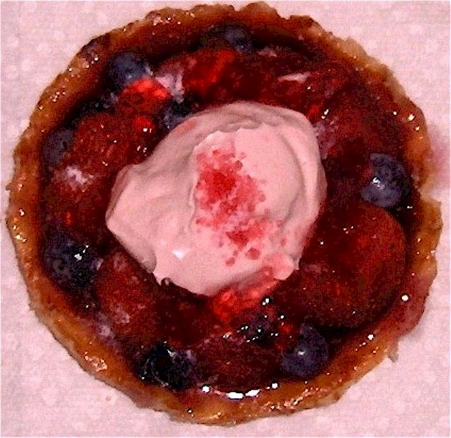 A home-made, French-style, mixed-fruit, luxury, individual tart. Made from dessert pastry with ground almonds; strawberries & blueberries; and blueberry jam. Glazed with strawberry jelly, and topped with whipped double-cream laced with strawberry liqueur. Liberally dusted with reddened, coarse, cinnamon-flavoured sugar - mixed with crushed sherbert bon-bon.