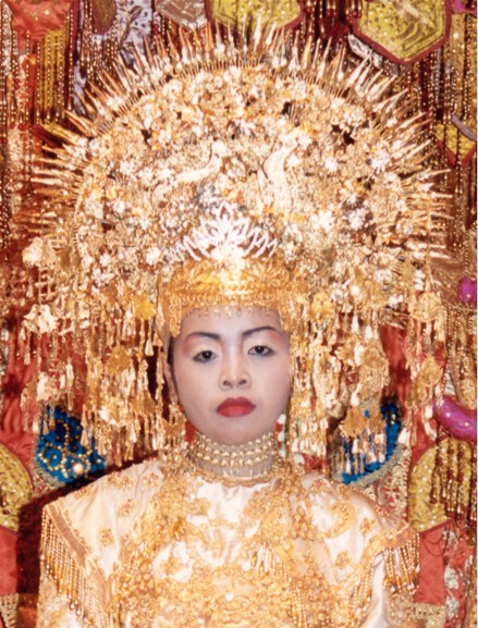 A bride at a traditional wedding in Padang in West Sumatra, Indonesia. She doesn't look too happy - perhaps because of the weight of her metal head-gear. Her costume is traditional and authentic, being over 100 years old. Gail requested this picture.