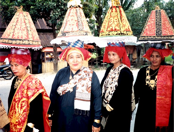 I asked this lady; one of a line of about 40 bridesmaids in a wedding procession passing through the old town of Solok; if I could take her photograph, and she obliged very positively and with formidable determination. I often try to interpret the facial expressions of her neighbours in the line-up. The 'lamp-shades' on their heads are actually hats !!