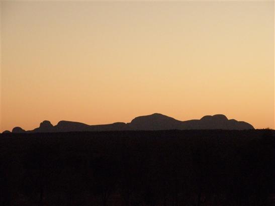 silhouetting a mountain range close to Uluru. Can you see a reclining Homer Simpson?