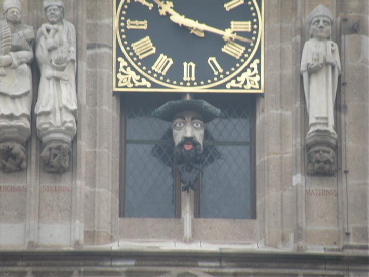 Has a face under it that sticks it's tongue out whenever the clock chimes, in response to the statue across the square mooning  City Hall.