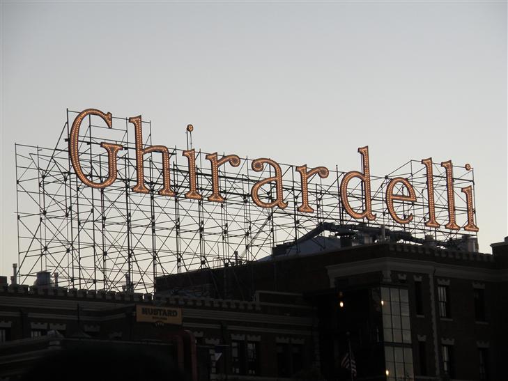 sign above the factory with faint sunset colors. Taken from in line waiting for the Cable Car.