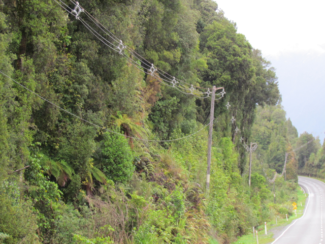 Poles are so close to the hillside that the wires are separated by spacers.