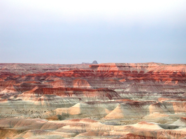 Truly beautiful rock colors and shapes with a mountain from the Hopi Indian Reservation in the background.  This photo was taken with the sun low in the west, so the red colors  were dominant.  While the rock is beautiful, the rugged and dry topography makes one wonder how any animal or human life survives in such surroundings.