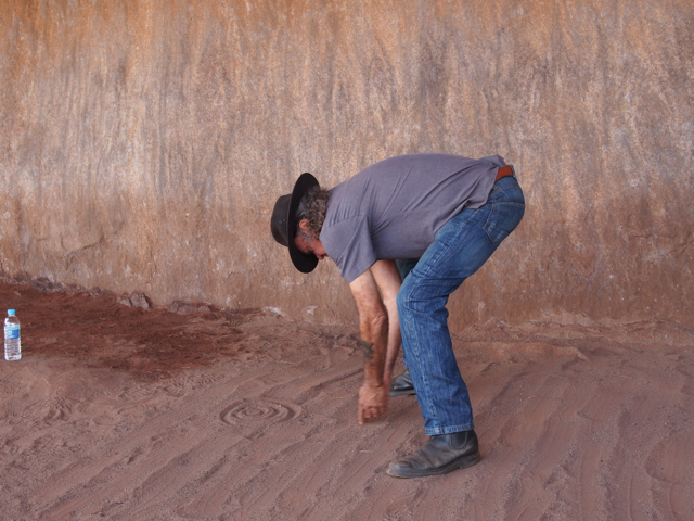 Drawing his story of Creation in the sand